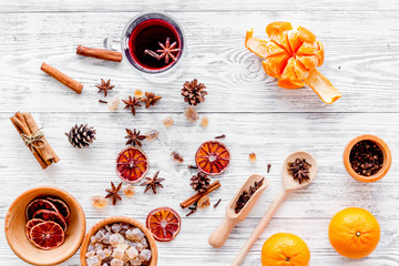 Hot mulled wine or grog cooking for new year celebration with oranges and spices ingredients on light background flat lay