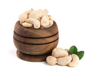 Cashew in a wooden bowl with leaf isolated on white background