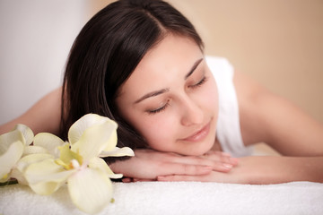 Fototapeta na wymiar people, beauty, spa, healthy lifestyle and relaxation concept - close up of beautiful young woman lying with closed eyes and having face or head massage in spa