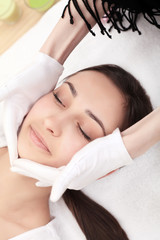 Fototapeta na wymiar people, beauty, spa, healthy lifestyle and relaxation concept - close up of beautiful young woman lying with closed eyes and having face or head massage in spa