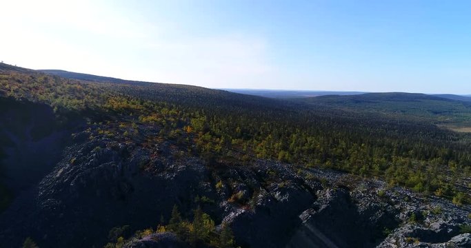 Tunturi mountain, Cinema 4k aerial view over a canyon, pine trees and stones, in pyha-luosto national park, on a sunny and colorful autumn day, in lapland or Lappi, Finland