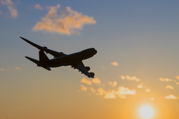 Airplane flying in the blue sky with pink clouds. Take off.