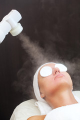 The procedure of steaming the skin of the face of a young woman before cleaning the skin, in a...