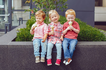 Group portrait of three white Caucasian cute adorable funny children toddlers sitting together...