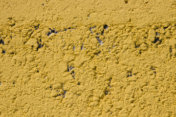 Closeup of the texture of yellow road paint.