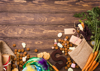 Dutch holiday Sinterklaas background with gifts, pepernoten, chocolate letter, sweets and childrens shoe with carrots for Santa's horse. Flat lay with copy space.