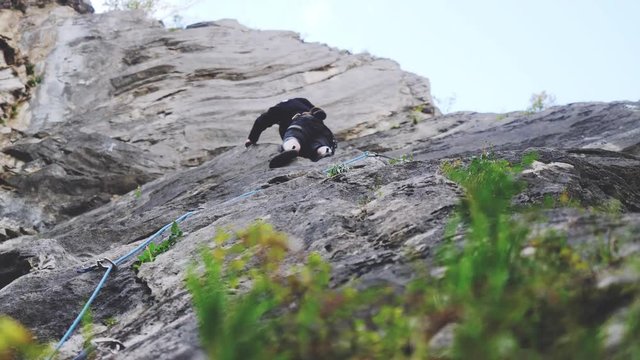 Extreme rock climber climbs difficult route view through the grass on the mountains. 3840x2160