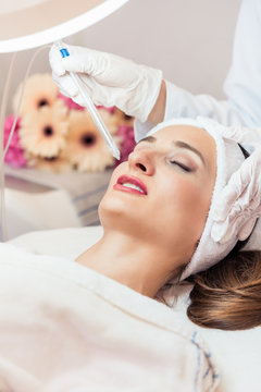 Beautiful woman relaxing during non-invasive facial treatment for rejuvenation in a contemporary beauty center with innovative equipment