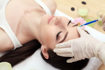 Hands of cosmetologist making injection in face, lips. Young woman gets beauty facial injections in salon. Face aging, rejuvenation and hydration procedures. Aesthetic cosmetology. Close up.