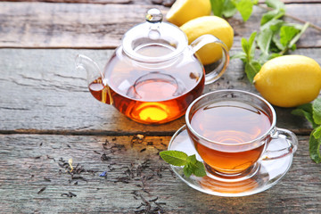 Cup of tea with teapot on grey wooden table