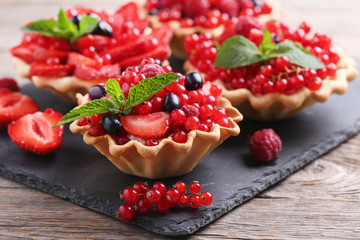 Dessert tartlets with berries on grey wooden table