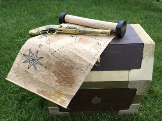An old treasure map and a pirate gun on a treasure chest