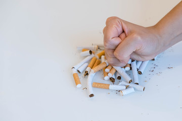 Stop smoking. Close up of male hand breaking cigarettes with his fist. Isolated and copy space in left side