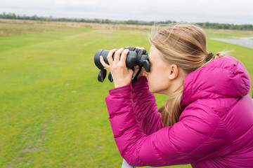 blonde woman looks in binocular