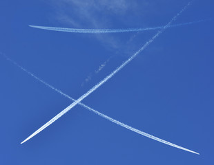 A jet plane flying overhead diagonally with condensation trail.