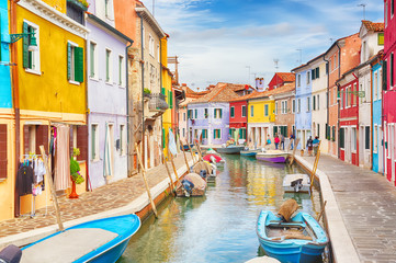 Colorful houses with boats in Burano island with cloudy blue sky near Venice, Italy. Popular and famous tourist place. - obrazy, fototapety, plakaty