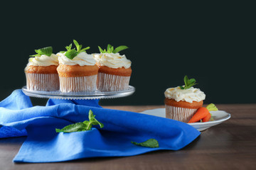Glass stand with delicious carrot cupcakes on table