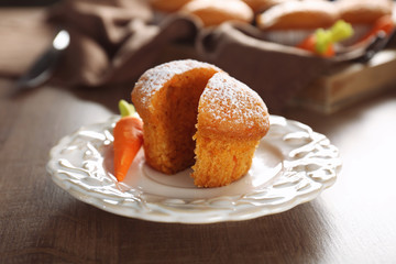 Plate with delicious carrot muffin on wooden table