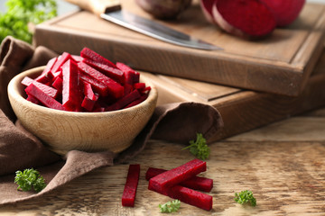 Bowl with sliced beetroot on wooden table