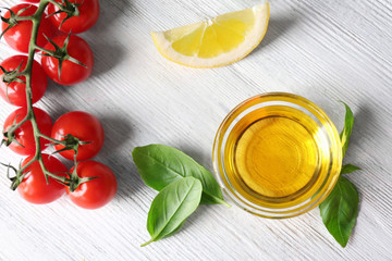 Bowl with basil oil, green leaves and tomatoes on wooden table