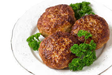 Homemade cutlets with parsley on a white plate and white background.