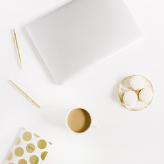 Modern gold stylized home office desk with laptop, macaroons, pen, coffee mug on white background. Flat lay, top view lifestyle concept.
