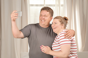 Overweight couple taking selfie at home