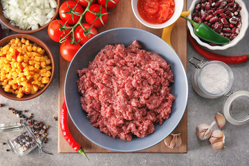 Raw minced meat and vegetables on kitchen table