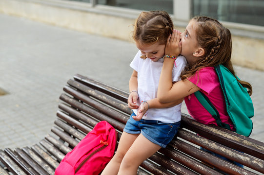 Older sister telling a secret to her younger sister