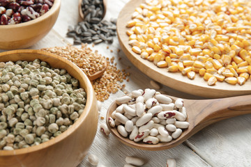 Different grains in kitchenware on wooden background