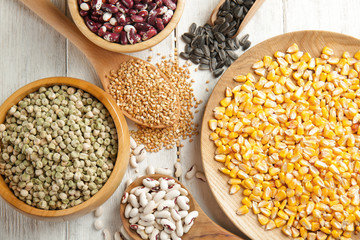 Different grains in kitchenware on wooden background
