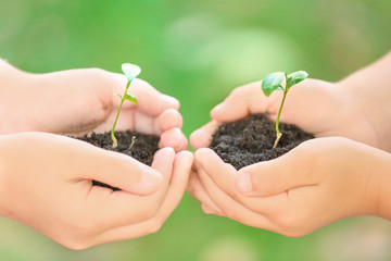 Kids holding soil and plants in hands outdoors