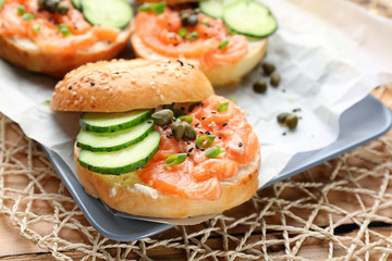 Tasty bagel with salmon on plate, closeup