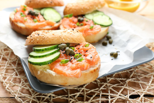 Tasty bagel with salmon on plate, closeup