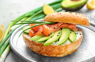 Delicious salmon bagel on metal tray, closeup