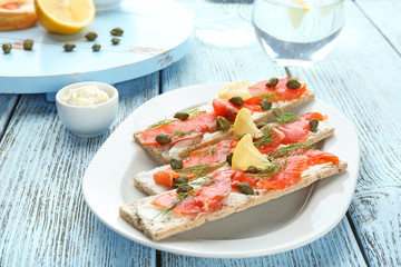 Tasty crispbread sandwiches with salmon and capers on plate