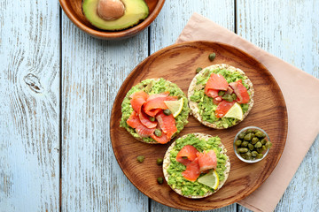 Tasty crispbread sandwiches with salmon and avocado on plate