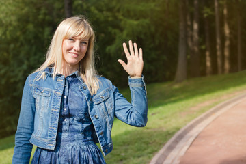 Beautiful young woman smiling and waving with her hand looking at camera. Saying hello.