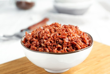 Bowl with red rice on board, closeup