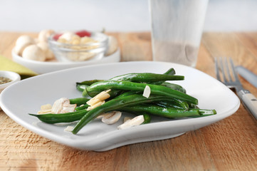 Plate with delicious green beans, almond and mushrooms on table