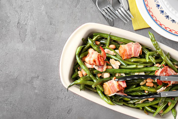 Casserole dish with delicious green beans and fried bacon on table