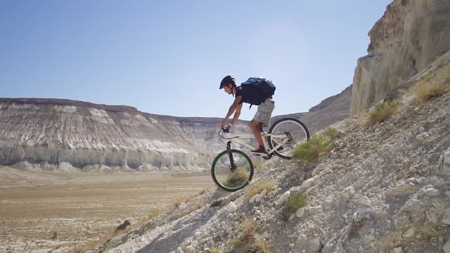 A young man on a bicycle is rolling from the mountain. Slow motion