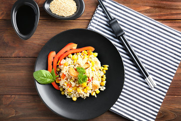 Plate with brown rice and vegetables on wooden table