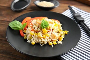 Plate with brown rice and vegetables on wooden table