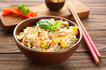Bowl with brown rice and vegetables on wooden table