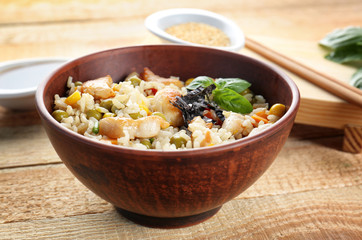 Bowl with brown rice and vegetables on wooden table