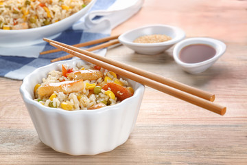 Bowl with brown rice and vegetables on wooden table