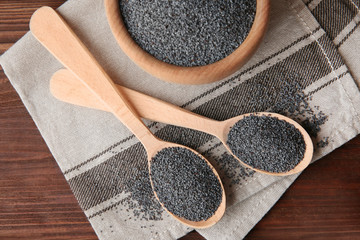 Ripe poppy seeds in kitchenware on fabric