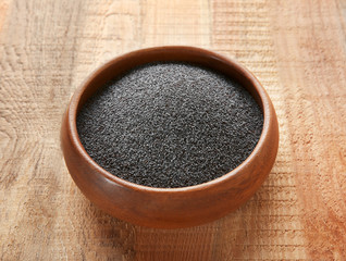 Ripe poppy seeds in bowl on wooden background