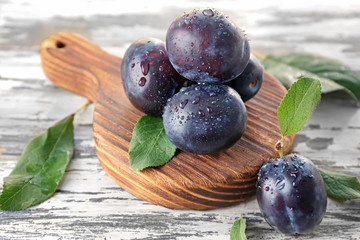 Fresh ripe plums on wooden board